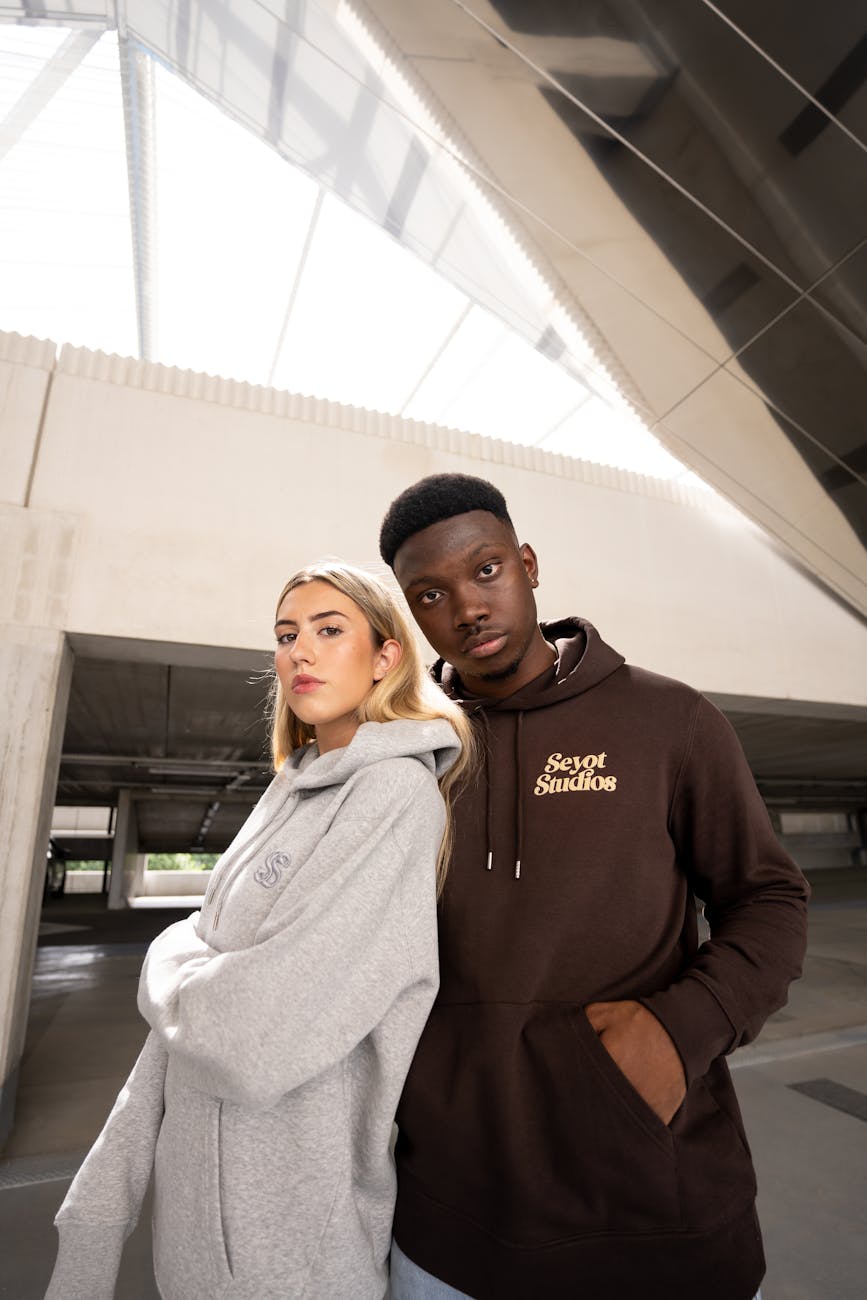 Young adults posing in trendy hoodies in a contemporary urban setting.